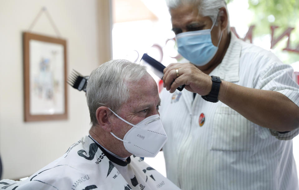 Barber Rudy Soliz gives Brian Barnett a haircut at the San Marcos Barber Shop in San Marcos, Texas, Thursday, May 21, 2020. Businesses in Texas closed due to the COVID-19 pandemic continue to open in phases; bars are permitted to open Friday. (AP Photo/Eric Gay)