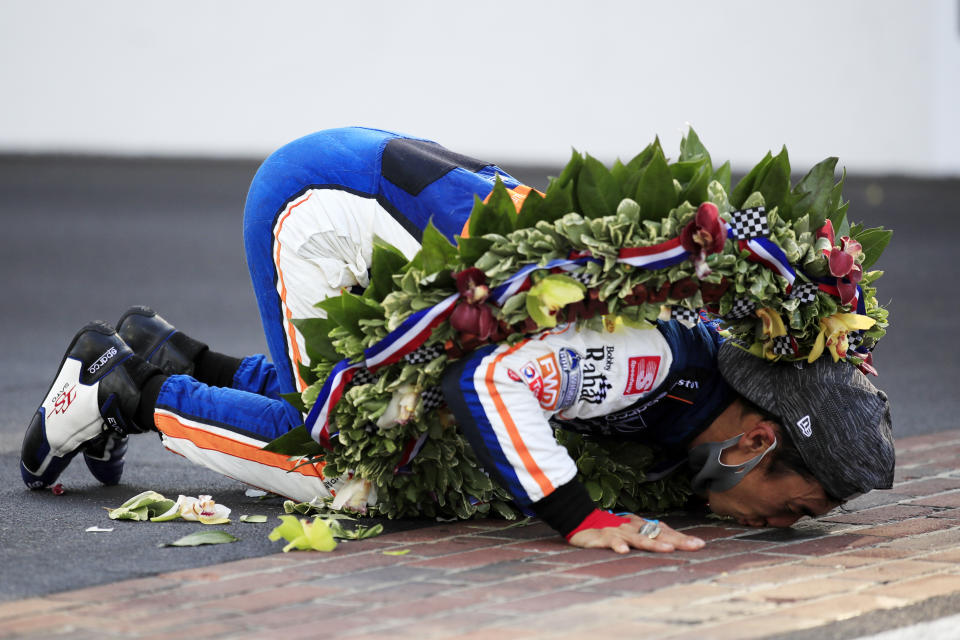 Takuma Sato celebrates by kissing the bricks after winning.