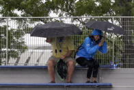 Tennis fans take cover under umbrellas as rain begins to fall during the second round of the US Open tennis championships, Wednesday, Sept. 1, 2021, in New York. (AP Photo/Elise Amendola)