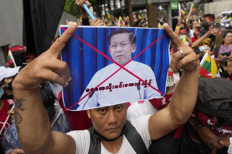 A Myanmar nationals living in Thailand holds a picture of Senior Gen. Min Aung Hlaing, head of the military council as they protest outside Myanmar's embassy in Bangkok, Thailand, Tuesday, July 26, 2022. International outrage over Myanmar's execution of four political prisoners intensified Tuesday with grassroots protests and strong condemnation from world governments, as well as fears the hangings could derail nascent attempts to bring an end to the violence and unrest that has beset the Southeast Asian nation since the military seized power last year.(AP Photo/Sakchai Lalit)