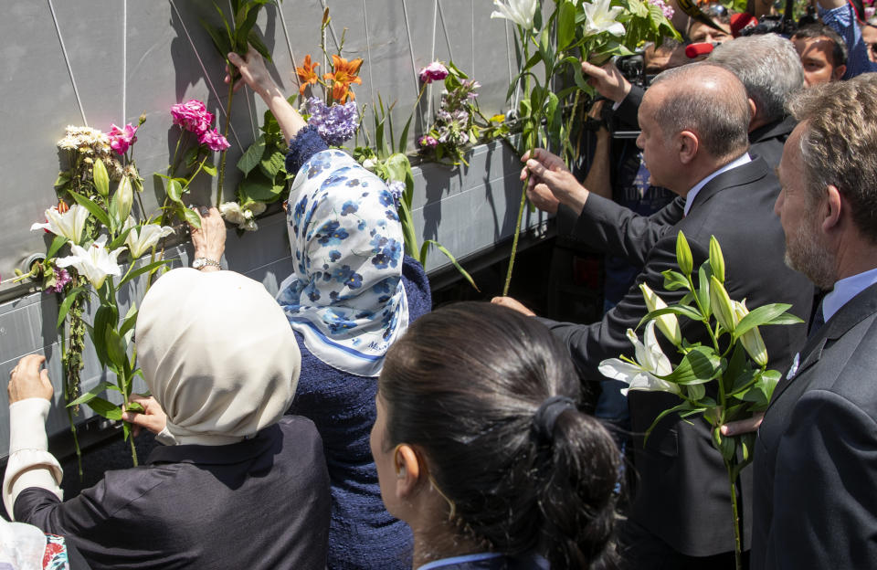 Turkey's president Rejep Tayyip Erdogan, center right, pays his respect as he with others decorate the vehicle carrying the remains of 33 victims of the Srebrenica massacre, in Sarajevo, Bosnia, Tuesday, July 9, 2019. The remains will be buried in Potocari near Srebrenica, on July 11, 2019, 24 years after Serb troops overran the eastern Bosnian Muslim enclave of Srebrenica and executed some 8,000 Muslim men and boys, which international courts have labeled as an act of genocide (AP Photo/Darko Bandic)