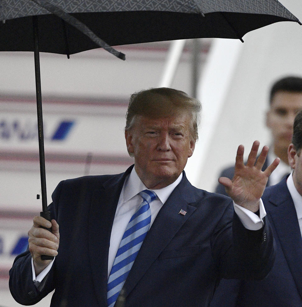 U.S. President Donald Trump waves as he arrives at the Osaka International Airport to attend the G-20 Summit in Osaka, western Japan. (Kyodo News via AP)