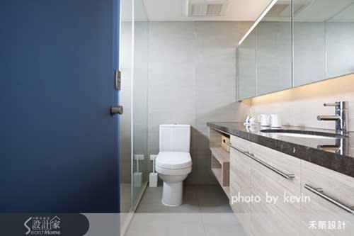 廁所的藍色大門和其他空間點綴的藍色相呼應，木質和深色大理石搭檔的洗手檯，上方宛如從牆壁長出的中空鏡面，內藏間接光設置，讓光也隨著鏡面流瀉而出。