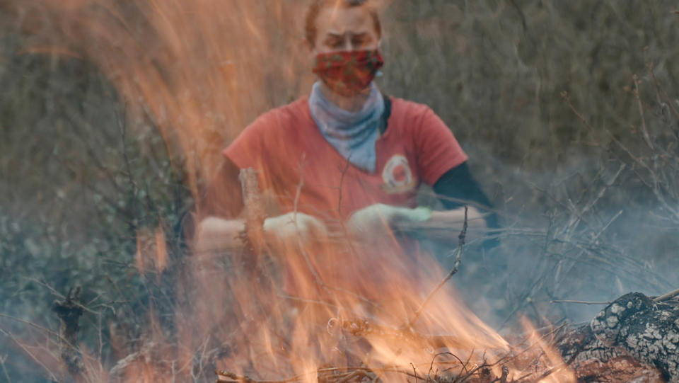 Stephanie Beard, the communication specialist for the conservation nonprofit Pepperwood, throws more dried brush on a flaming burn pile. (Photo: Ed Kashi/VII)