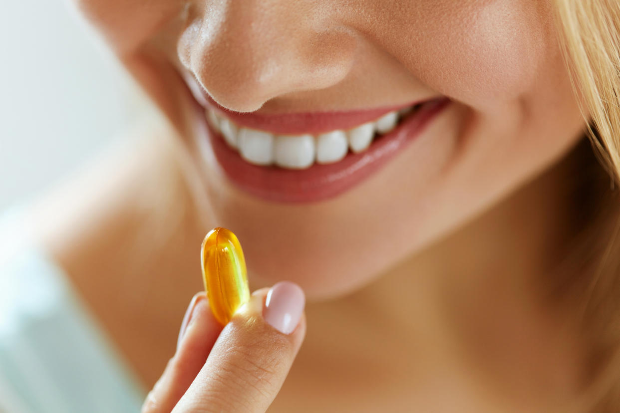 Vitamin And Supplement. Closeup Of Beautiful Young Woman Taking Yellow Fish Oil Pill. Female Hand Putting Omega-3 Capsule In Mouth. Healthy Eating And Diet Nutrition Concepts. High Resolution Image