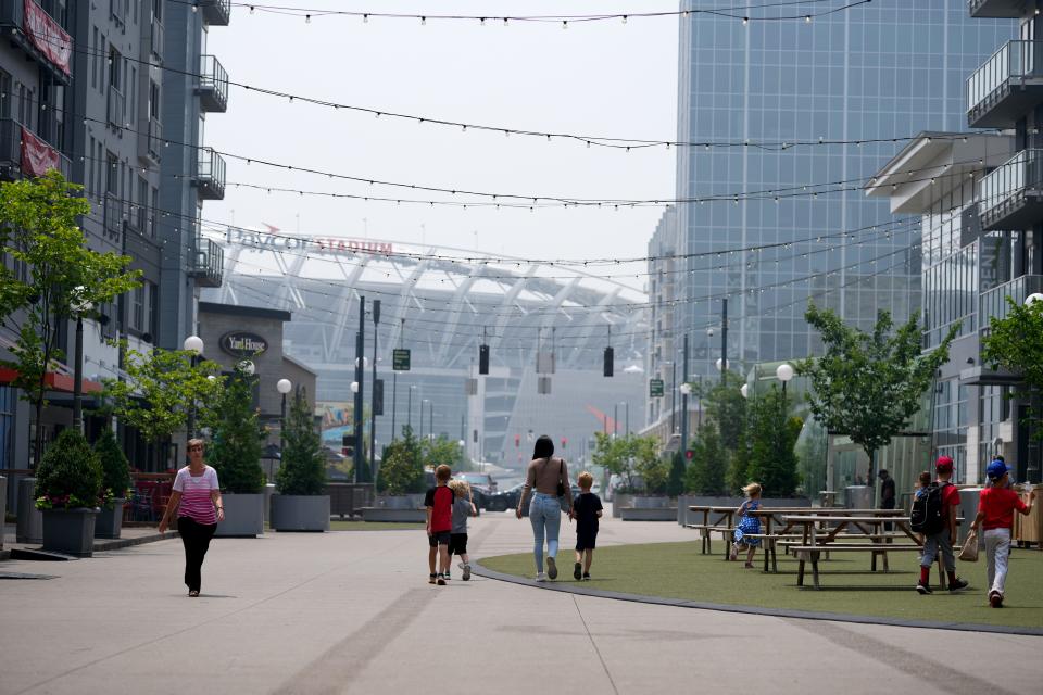 People walk along the pedestrian-only area of Freedom Way, with Paycor Stadium in the background, Wednesday, June 28, 2023, in Downtown Cincinnati.