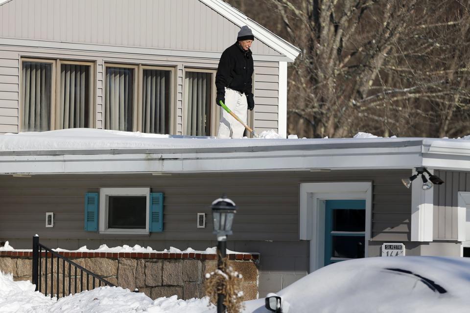 A Somersworth resident shovels his roof Sunday, Jan. 30, 2022, following a blizzard the previous day.