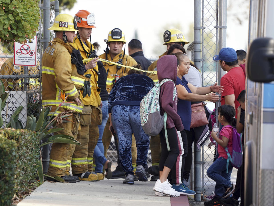 Firefighters allow parents into Park Avenue Elementary School where multiple people were treated for jet fuel exposure in Cudahy, Calif., on Tuesday, Jan. 14, 2020. A jet returning to LAX dumped its fuel over the neighborhood and the school. Affected people at the school were treated for skin and eye irritation. No patients were transported to hospitals. (Scott Varley/The Orange County Register via AP)