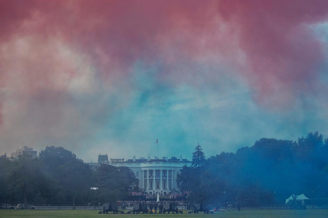 The White House in obscured by Red and Blue smoke floating on the Ellipse during a 