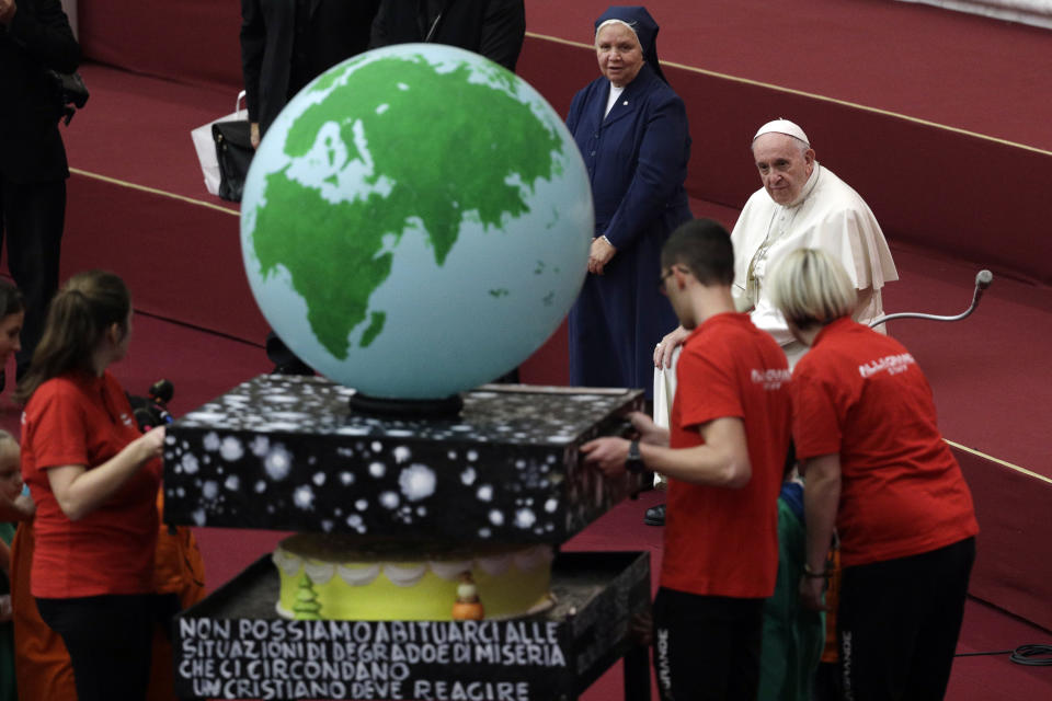 Pope Francis looks at a cake he was offered on the eve of his 82nd birthday during audience with children and family from the dispensary of Santa Marta, a Vatican charity that offers special help to mothers and children in need, in the Paul VI hall at the Vatican, Sunday, Dec. 16, 2018. (AP Photo/Gregorio Borgia)