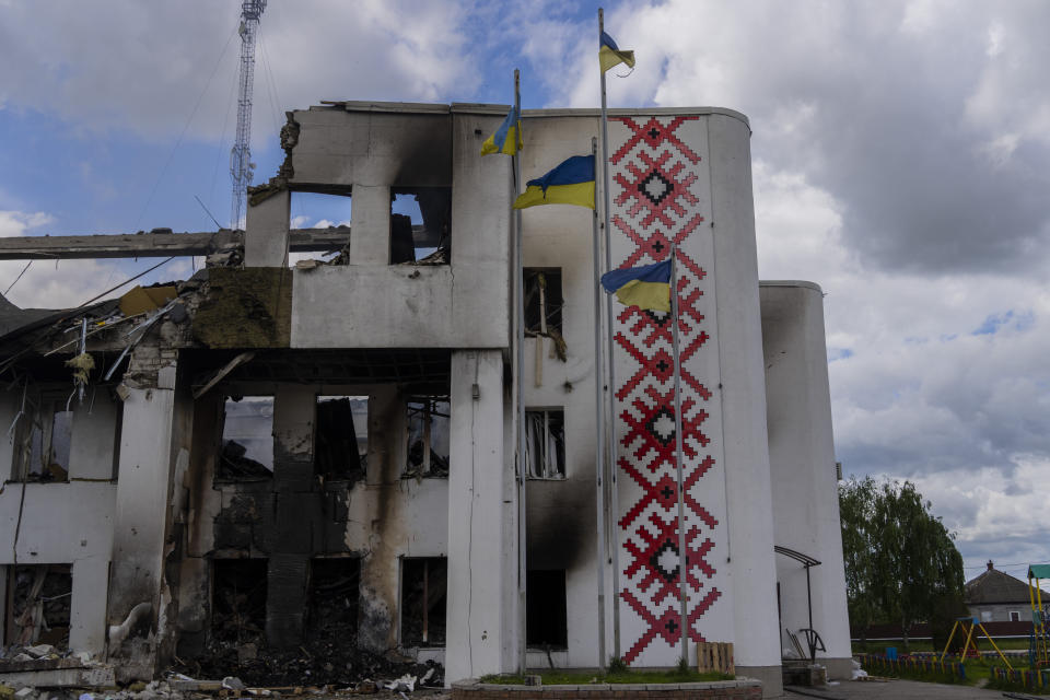 Ukrainian flags flutter outside a destroyed cultural center in Derhachi, eastern Ukraine, Sunday, May 15, 2022. A Russian airstrike destroyed the venue on May 12. (AP Photo/Bernat Armangue)
