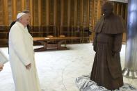 Pope Francis looks at a chocolate statue made in his likeness, which he received as a gift, in Paul VI's Hall at the Vatican, in this picture taken February 5, 2014 and released February 6, 2014. REUTERS/Osservatore Romano