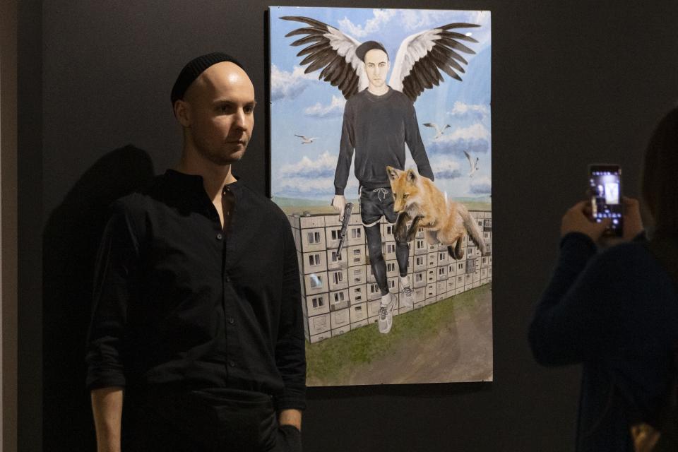 In this photo taken on Saturday, Oct. 26, 2019, self-taught painter Pasmur Rachuiko, who offers an extreme outsider's view of Moscow reality, poses for a photo prior to an opening his exhibition in Gogol Center in Moscow, Russia. Moscow’s suburbs are the focus of a major international art exhibition that has just opened in the Russian capital. The exhibit uses contemporary art to explore the many hidden facets of life beyond the Russian capital’s nucleus. Austrian cultural attache says the ‘real’ Moscow where most of the city’s 12.6 million people live, is outside the center. (AP Photo/Alexander Zemlianichenko)