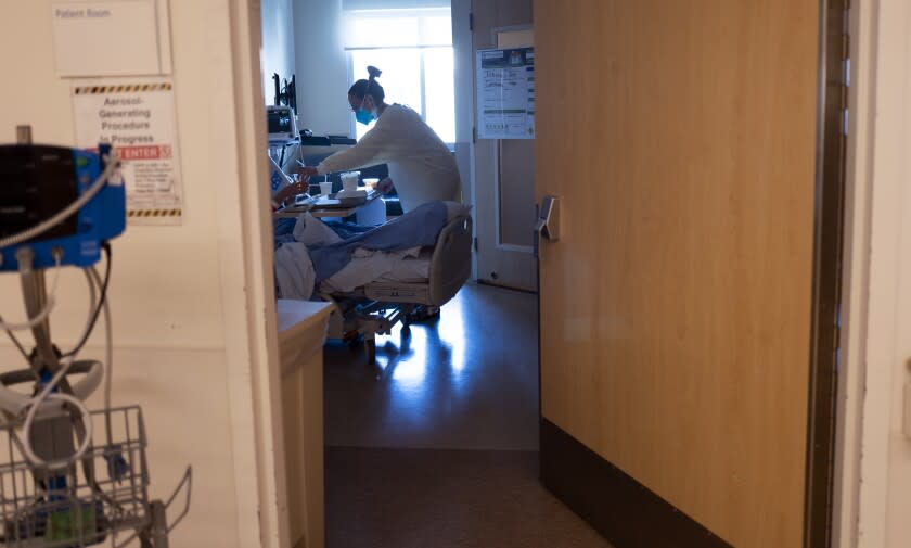 MISSION HILLS, CA - JANUARY 14: Palliative care physician Dr. Marwa Kilani, MD, hands a patient some liquid inside the covid unit at Providence Holly Cross Medical Center Thursday, Jan. 14, 2021 in Mission Hills, CA. (Francine Orr / Los Angeles Times)