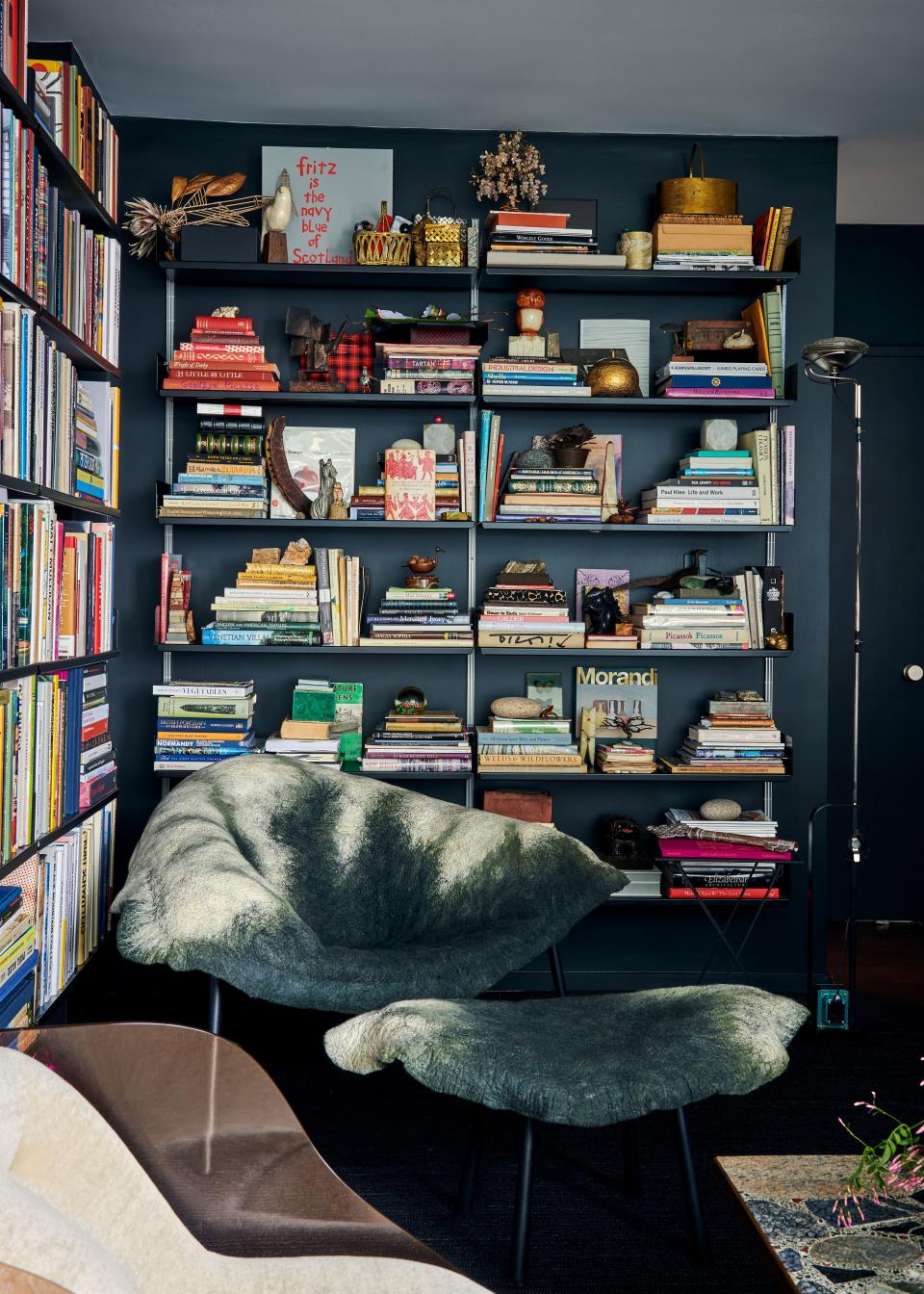 This corner of the library belongs to Mann’s partner, Fritz Karch, so to speak. The shelves on the back wall are stocked with a miscellany of vintage finds, part of Karch’s ever-growing collection of curiosities. The abstract armchair and ottoman are by Israeli designer Ayala Serfaty, purchased at Maison Gerard.