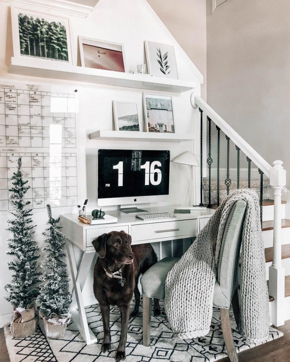 a desk and floating shelves under a staircase