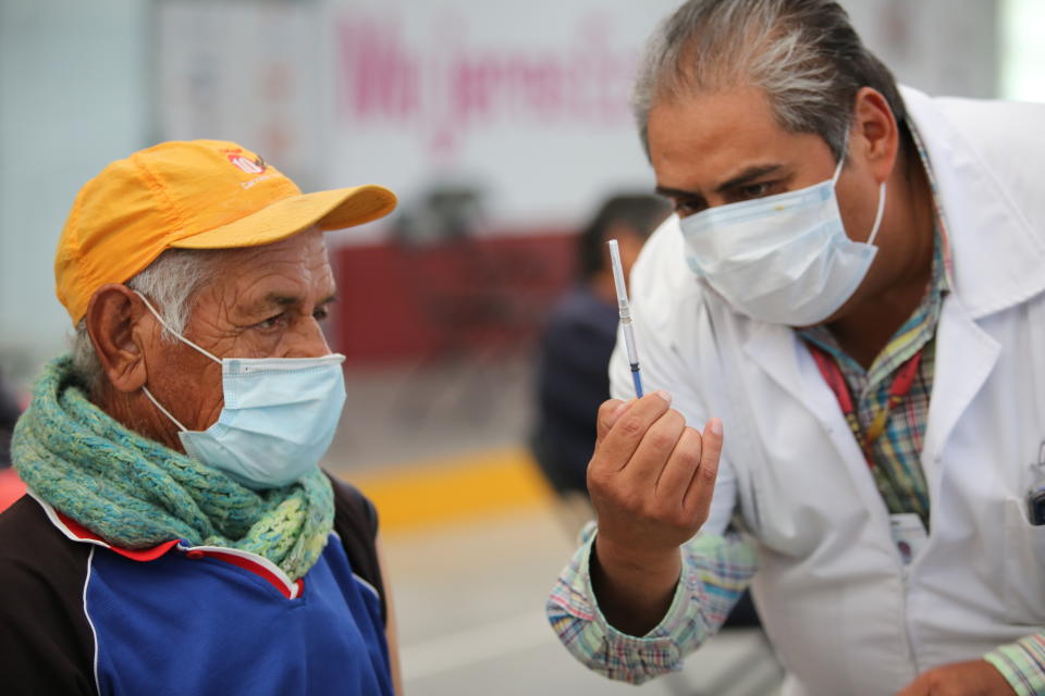 Un enfermero muestra a un anciano una jeringa preparada con una dosis de la vacuna de Sinovac contra el coronavirus antes de aplicársela en el puesto de inoculación instalado en el Centro Cultural y Deportivo Las Américas, en Ecatepec, Estado de México, el sábado 3 de abril de 2021. (AP Foto/Ginnette Riquelme)