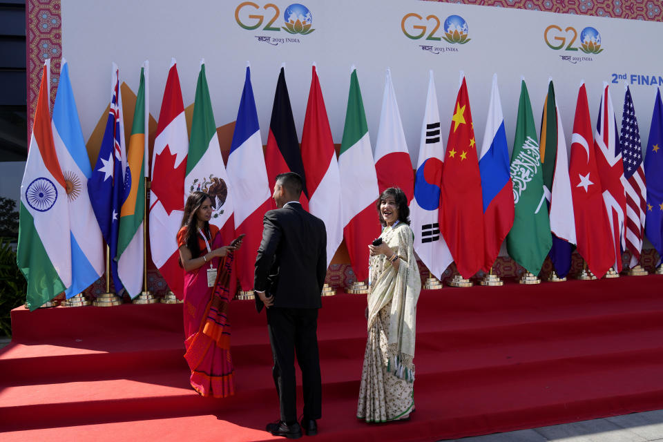 Delegates interact in front of flags of participating countries displayed at the venue of G-20 financial conclave on the outskirts of Bengaluru, India, Wednesday, Feb. 22, 2023. Top financial leaders from the Group of 20 leading economies are gathering in the south Indian technology hub of Bengaluru to tackle challenges to global growth and stability. India is hosting the conclave for the first time in 20 years. (AP Photo/Aijaz Rahi)