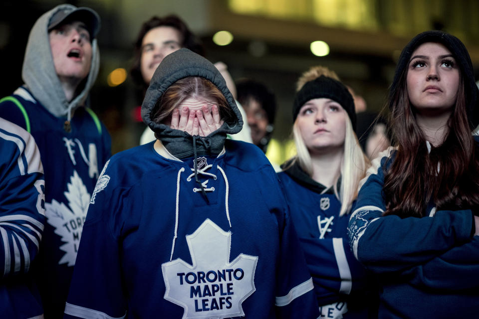 Fans react in Toronto on Tuesday, April 23, 2019, as the Toronto Maple Leafs lose to the Boston Bruins and are eliminated from the Stanley Cup NHL hockey playoffs. Fans watched the action from Boston on large outdoor screens in Maple Leaf Square in Toronto. (Christopher Katsarov/The Canadian Press via AP)