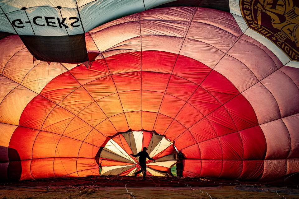 <p>Balloon pilots check the rigging inside a balloon canopy as they prepare for the first mass ascent from Filton, Bristol, during 'Fiesta Fortnight' that will see hundreds of balloons above the skies of Bristol over two weeks, culminating in the Bristol International Balloon Fiesta at Ashton Court Estate. Picture date: Wednesday August 4, 2021.</p>
