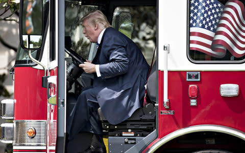 U.S. President Donald Trump sits in a fire truck while participating in a Made in America event at the White House in July - Credit: Bloomberg