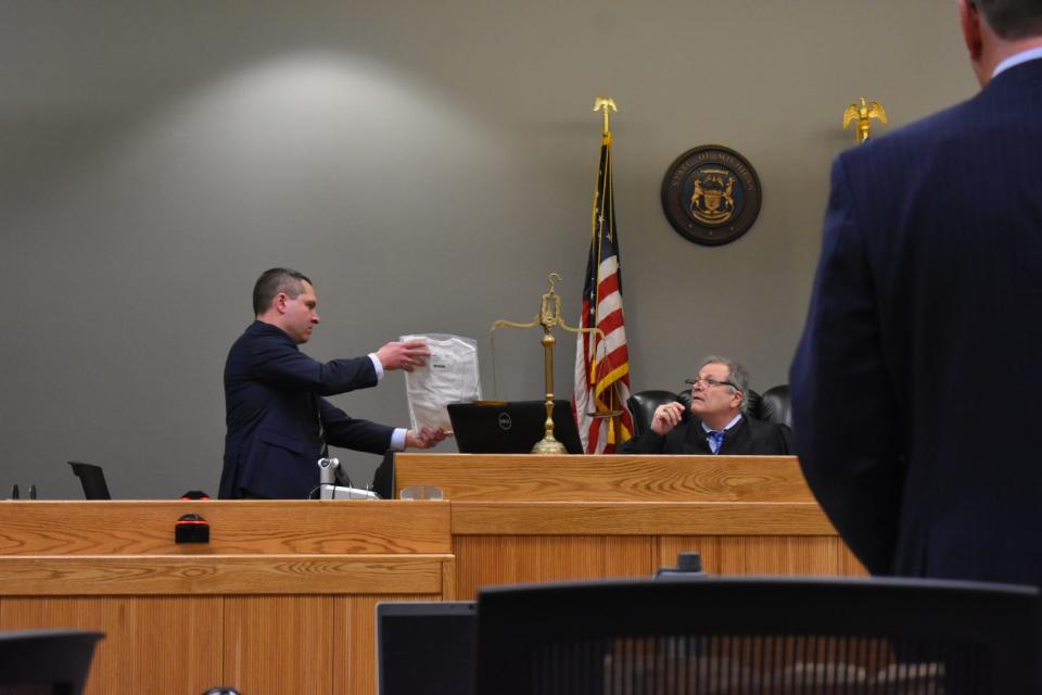 Michael Arntz from the Brighton Police Department holds up a white shirt that says, "Savior," on it, which was found in the back of Hayden Jagst's car.