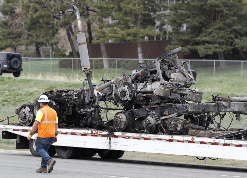 Workers clear debris, including the burned out section of a semi-truck, from Interstate 70 on Friday, April 26, 2019, in Lakewood, Colo., after a deadly pileup on Thursday. Lakewood police spokesman John Romero described it as a chain reaction of crashes and explosions from ruptured gas tanks. "It was crash, crash, crash and explosion, explosion, explosion," he said. (AP Photo/David Zalubowski)