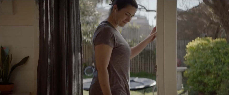 A woman in workout clothing in a Medibank commercial. She's returning to her family after exercising. The ad's been criticised for shaming mums.