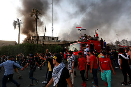 Iraqi protesters stand on a fire truck during an anti-government protest near the burnt building of the government office in Basra, Iraq September 7, 2018. REUTERS/Alaa al-Marjani