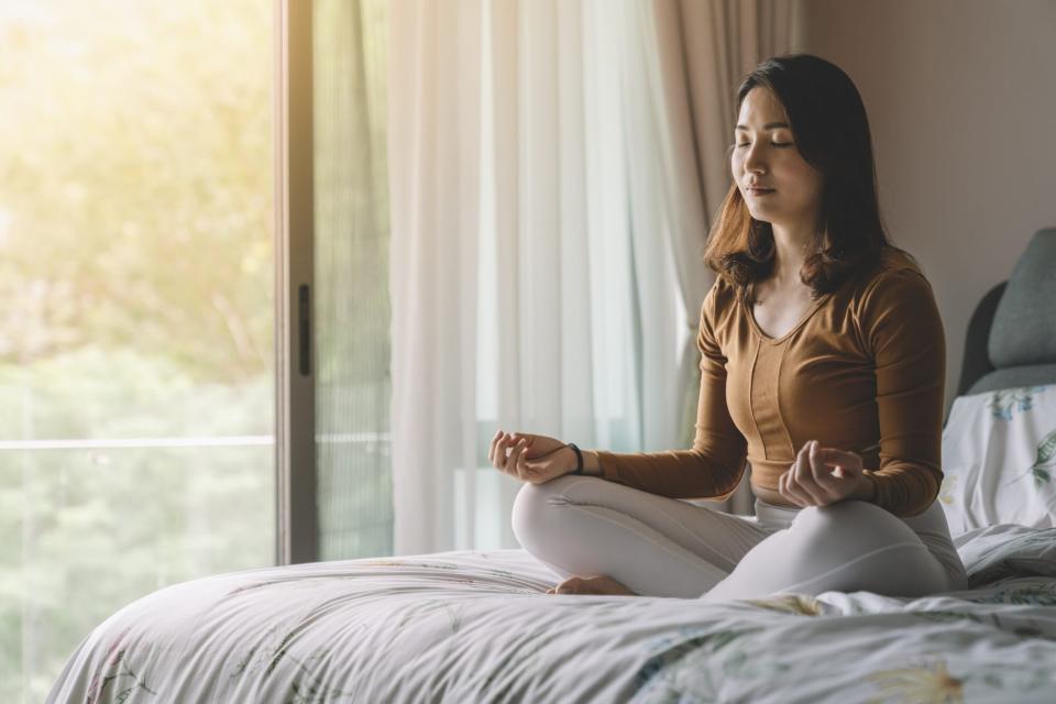 woman meditating on bed