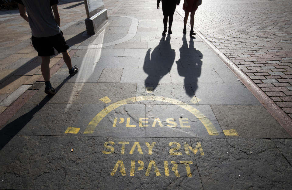 The changing face of the high street. People cast shadows walking past a social distancing information sign painted on the pavement on the high street in Dundee in Scotland, some six months on from the evening of March 23 when Prime Minister Boris Johnson announced nationwide restrictions. (Photo by Jane Barlow/PA Images via Getty Images)