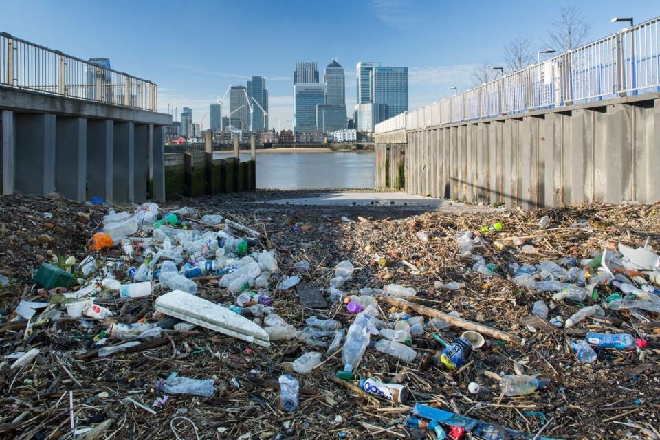 Rubbish left stranded by the tide on the River Thames with the towering Dockland banks in the background (Getty Images)