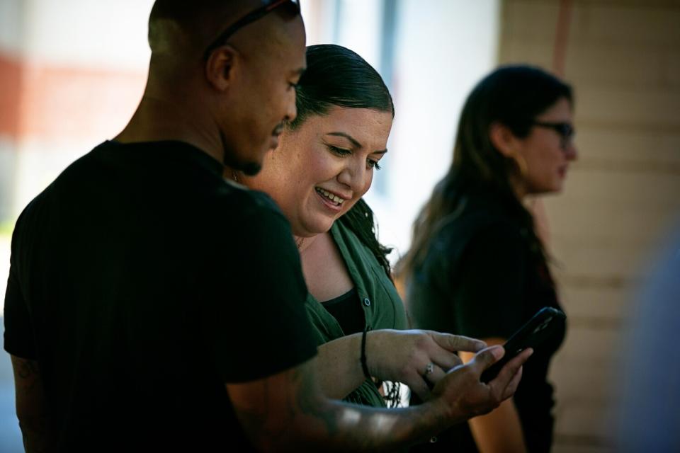 A woman looks at a man's phone as they chat