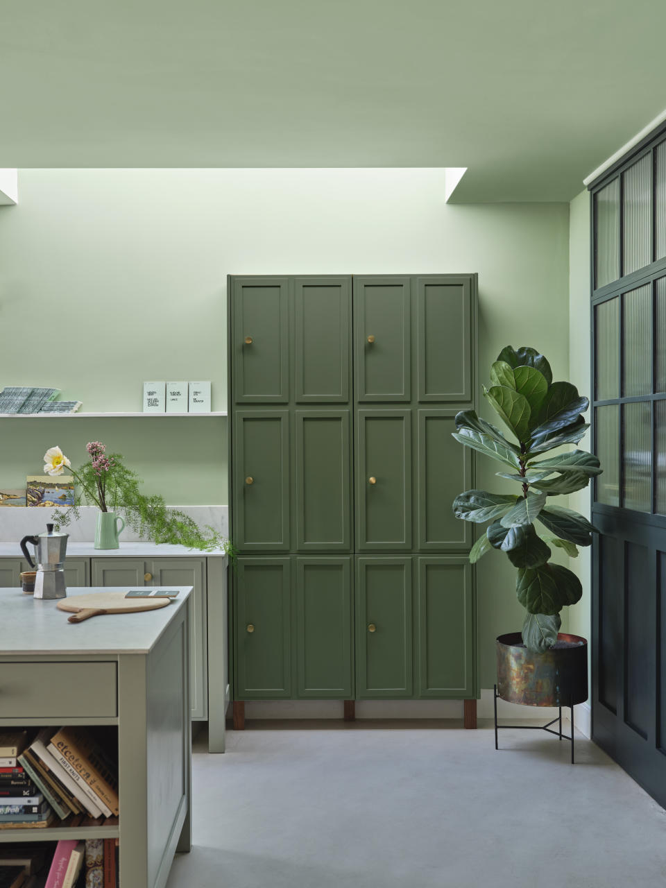 A kitchen with light green walls and a dark green pantry
