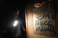 FILE - Viktor Shevchenko walks past graffiti that reads: 'Death to Russians', as he shows his house which had been damaged in a Russian attack in the Saltivka district in Kharkiv, Ukraine, July 1, 2022. As Russia's invasion of Ukraine grinds into its fifth month, some residents close to the front lines remain in shattered and nearly abandoned neighborhoods. One such place is Kharkiv's neighborhood of Saltivka, once home to about half a million people. Only perhaps dozens live there now, in apartment blocks with no running water and little electricity. (AP Photo/Evgeniy Maloletka, File)