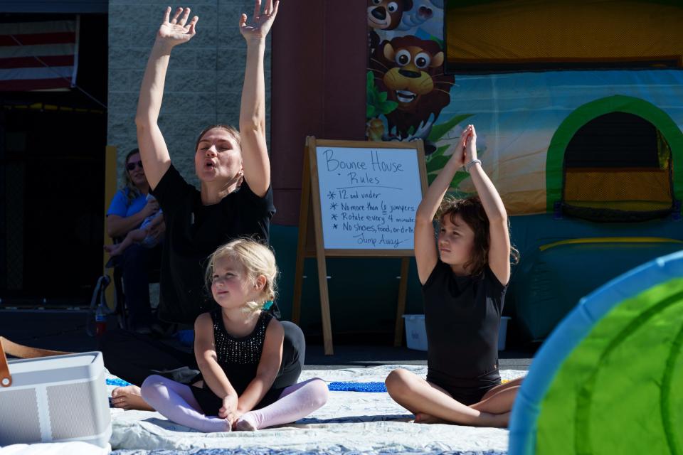 Juliana Klepimina (left) sits with daughters, Anastasia Suleyman, 3, and Valeria Suleyman, 6, as she leads a kid-friendly yoga activity at ESA Connection's Discover Enrichments! Educational Fair at Baker's MMA on Oct. 28, 2023, in Surprise, AZ.