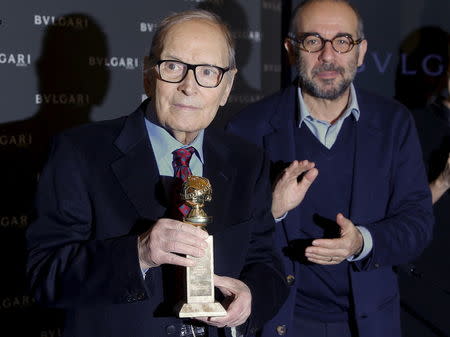 Italian composer Ennio Morricone pose with the Golden Globe trophy he received for his work on the movie "The Hateful Eight", as Italian director Giuseppe Tornatore applauds in Rome, Italy January 30, 2016. REUTERS/Tony Gentile