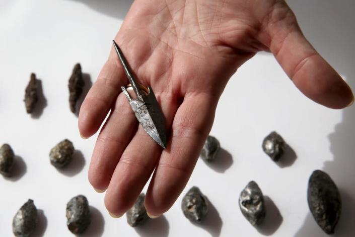 A member of the Israeli Antiquity Authorities displays on November 3, 2015 lead sling stones, bronze arrowheads and ballista stones at a site adjacent to Jerusalem's Old City walls where researchers claim to have found the remains of the Acra (AFP Photo/Gali Tibbon)