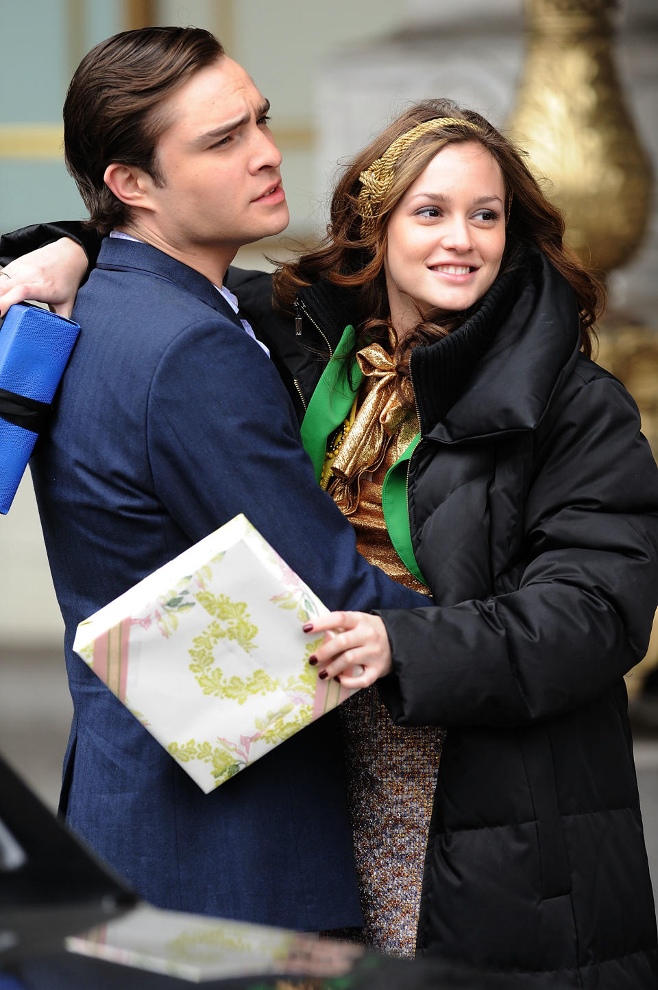 Actor Ed Westwick and actress Leighton Meester on set, in character with gift box and script