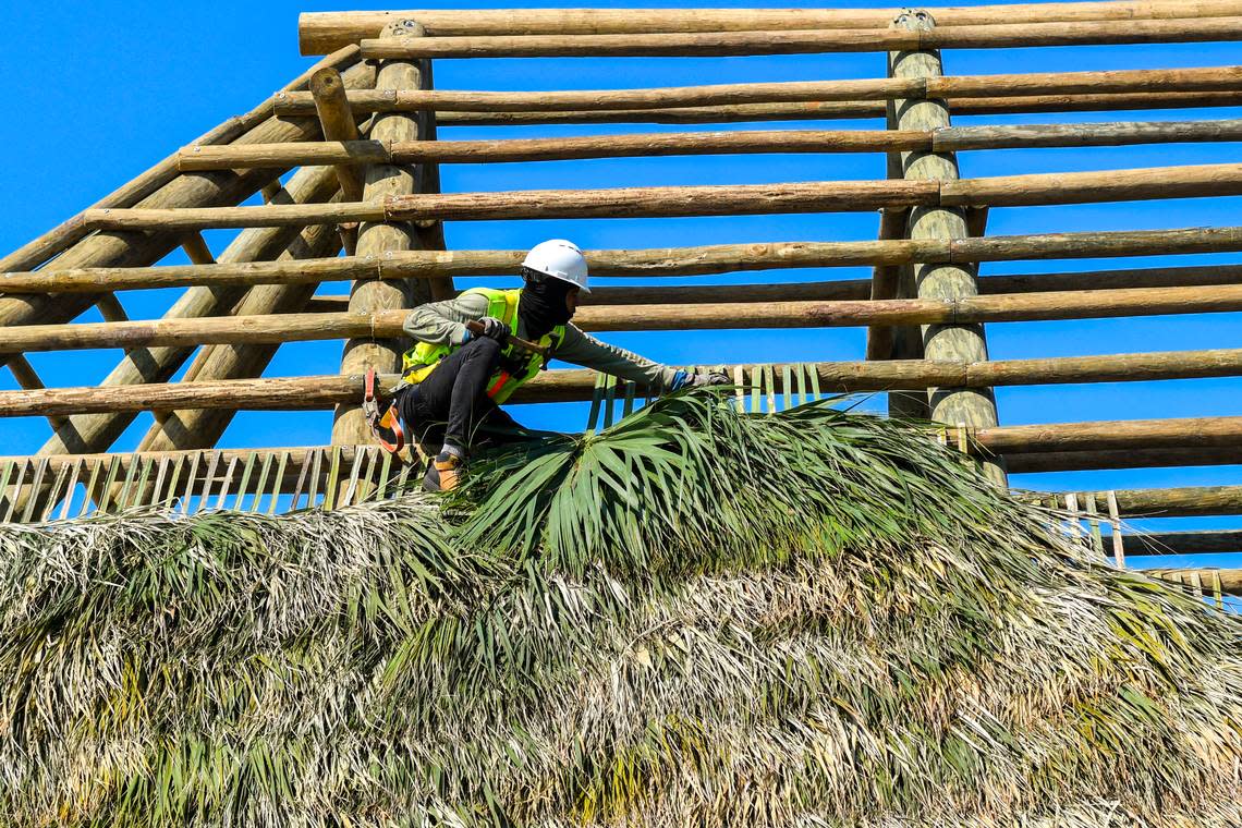 A roofer with Big Cypress Tiki Huts attaches a palm frond on Wednesday, April 24, 2024 as a new roof is built for The Beach House Hilton Head Island’s new tiki hut at Coligny Beach on Hilton Head.