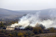 FILE - In this Thursday, Nov. 19, 2020 file photo, smoke rises from a burning house in Karmiravan village as ethnic Armenians leaving the the area, prior to the Azerbaijani forces being handed control in the separatist region of Nagorno-Karabakh. With Azerbaijan regaining control of land it lost to Armenian forces a quarter-century ago, civilians who fled the fighting decades ago are wondering if they can go back home now. But as Azerbaijani forces discovered when the first area was turned over Friday, Nov. 20 much of the recovered land is uninhabitable.(AP Photo/Sergei Grits, file)