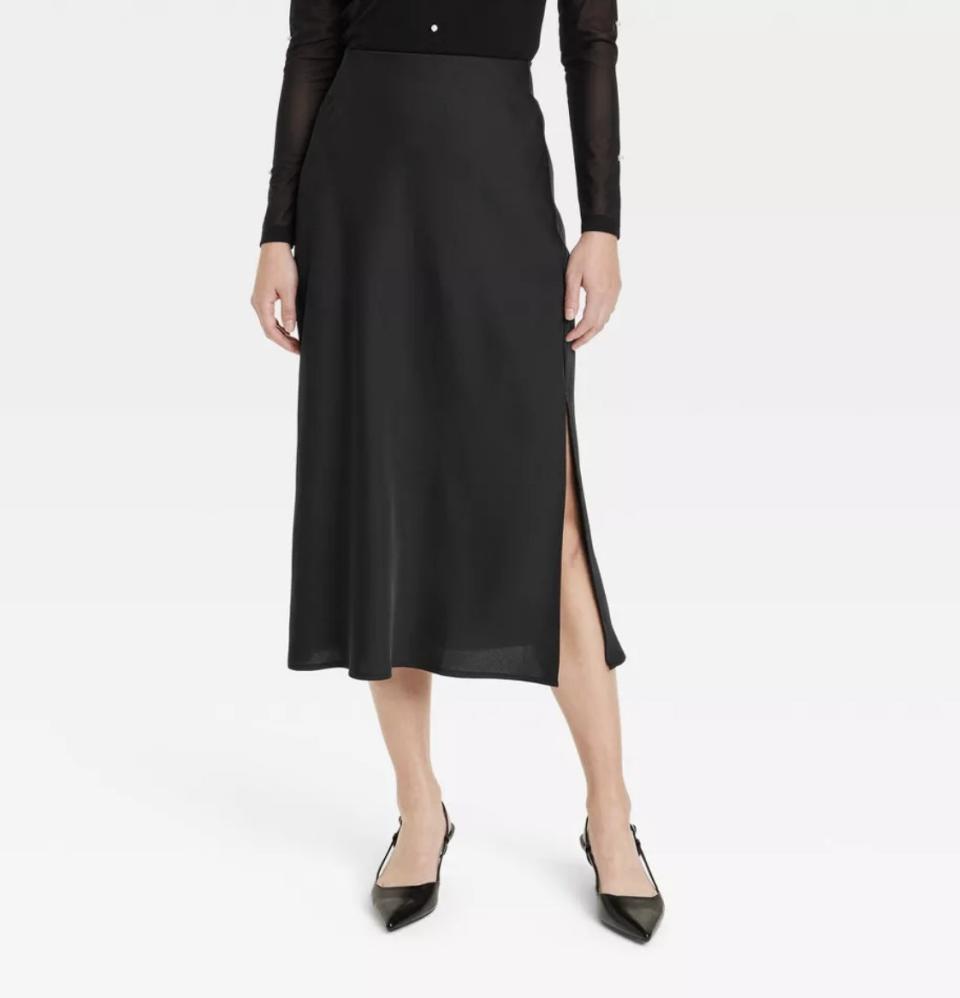 Person wearing a black midi skirt with a side slit and black pointed-toe heels