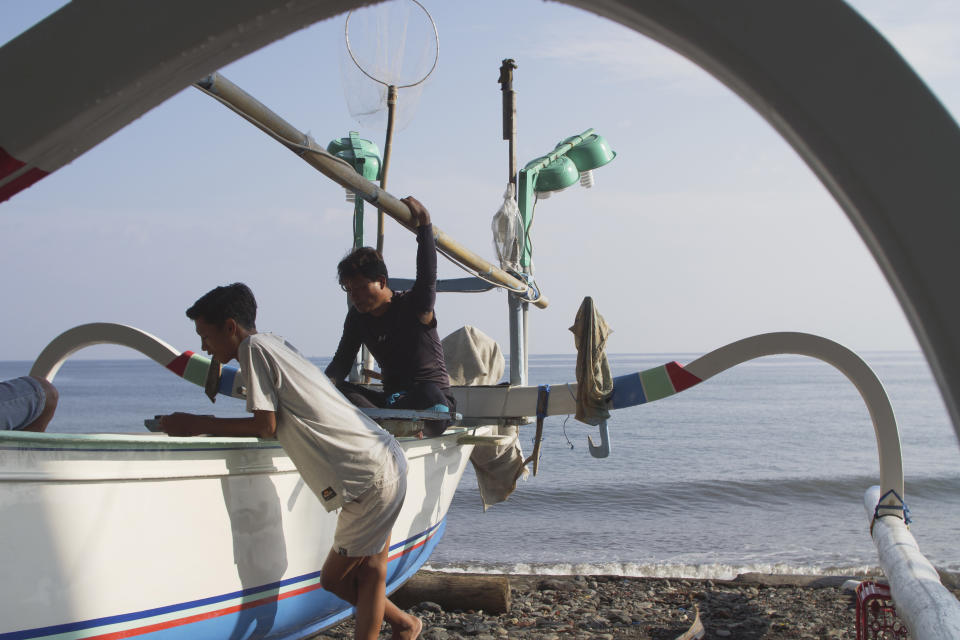 Villagers hang out near boats along the coast in Les, Bali, Indonesia, on April 9, 2021. The area is commonly used for aquarium fishing. (AP Photo/Alex Lindbloom)