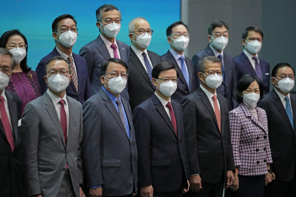 Hong Kong Chief Executive John Lee, bottom center, lines up with his new members of cabinet during a news conference in Hong Kong, Tuesday, July 5, 2022. Lee said Tuesday in his first news conference since taking the reins that he will work towards legislating easing restrictions for travelers, but that it must be balanced with limiting the spread of the coronavirus so as not to overwhelm the healthcare system. (AP Photo/Kin Cheung)