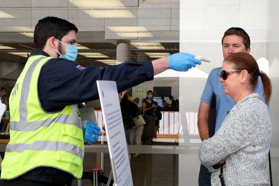 Customers have their temperatures taken before being allowed entry into the Apple Store in Perth. Source: AAP