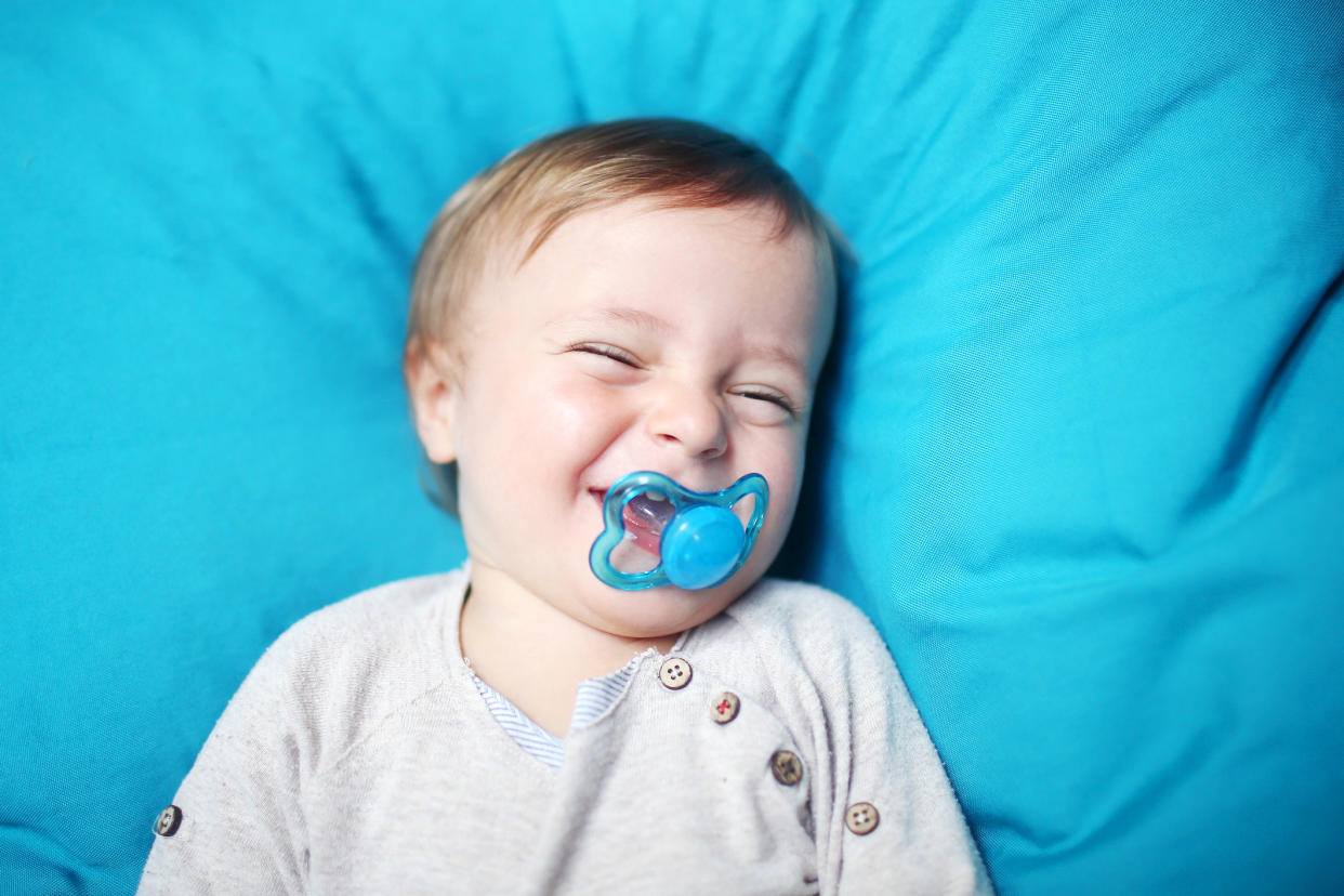 Toddler boy with pacifier surrounded by blue