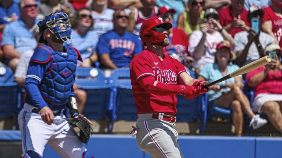 Toronto Blue Jays catcher Danny Jansen, left, looks on as Philadelphia Phillies' Bryce Harper hits a solo home run during the first inning of a spring training baseball game against the Philadelphia Phillies in Dunedin, Fla., Sunday, March 27, 2022. (Steve Nesius/The Canadian Press via AP)