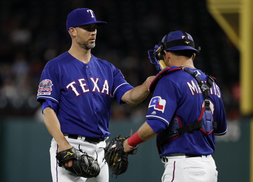 Texas Rangers starting pitcher Mike Minor visits with catcher Jeff Mathis (2) during the fourth inning of the team's baseball game against the Houston Astros in Arlington, Texas, Wednesday, April 3, 2019. (AP Photo/Tony Gutierrez)