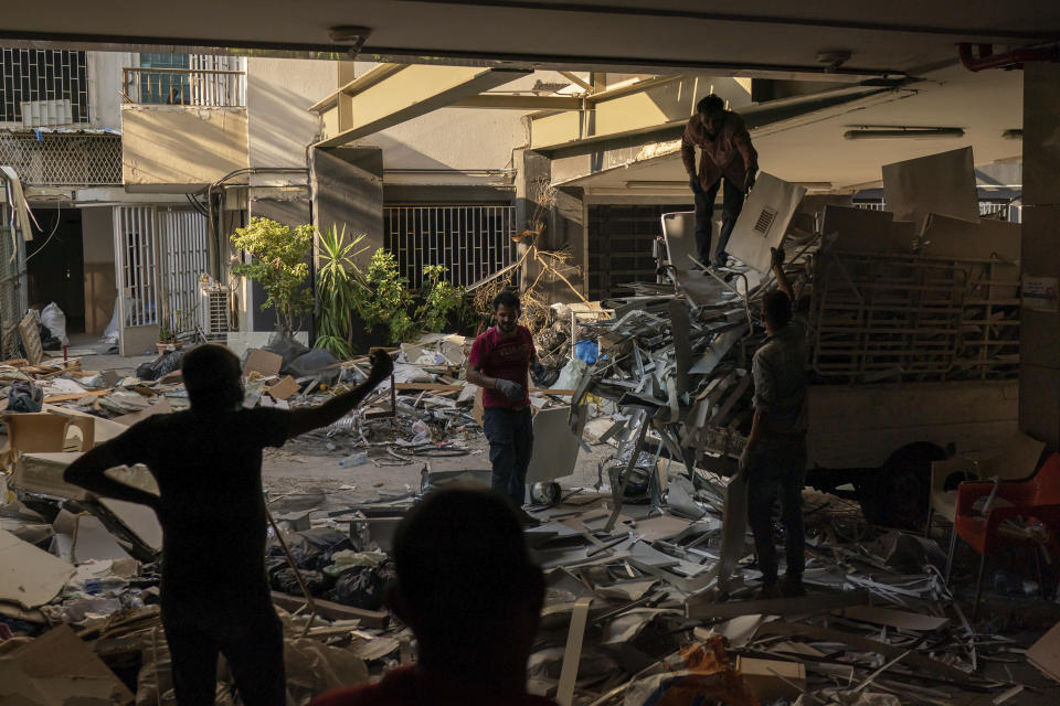 Workers remove debris from a hospital that was heavily damaged in last week's explosion that hit the seaport of Beirut, Lebanon, Tuesday, Aug. 11, 2020. The massive explosion is just the latest in multiple crises that have hit Lebanon the past year, including massive protests, economic collapse and the coronavirus pandemic. Some Lebanese, whether poor or middle class, now feel their resolve is simply broken. (AP Photo/Felipe Dana)