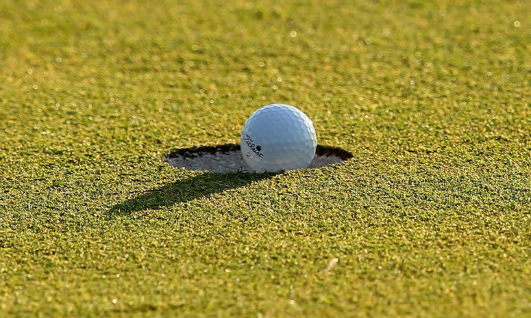 A golf ball falling into the cup.